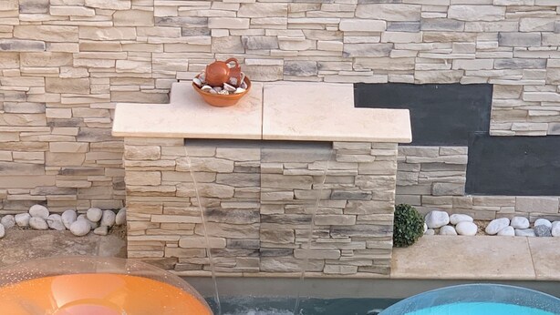 A swimming pool with two inflatable rings, one orange and one blue, and a stone wall in the background. - House with swimming pool facing south close to all shops  (Le Pontet)