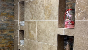 A bathroom with a stone wall, a tiled floor, and shelves with toiletries. - House with swimming pool facing south close to all shops  (Le Pontet)