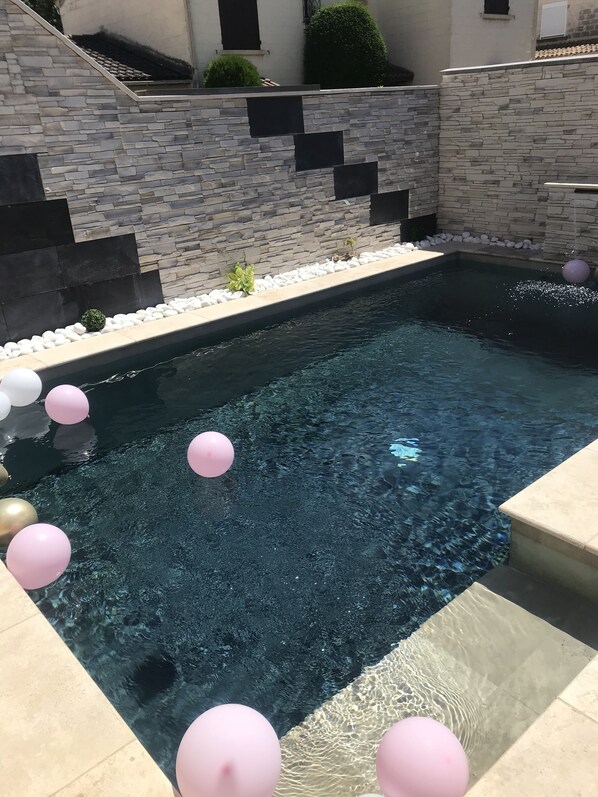 A swimming pool with a stone wall and steps leading up to it.