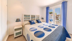 Un dormitorio con cama, mesitas de noche, una ventana con cortinas y vistas al exterior.