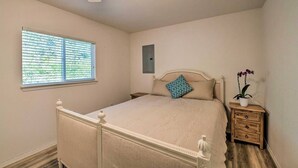 Ein Schlafzimmer mit Bett, Nachttisch, Fenster und Deckenventilator.