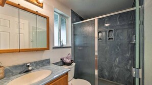 Ein Badezimmer mit Marmorwaschbecken, einer Duschkabine aus Glas und einer weißen Toilette.