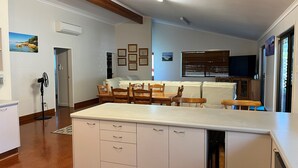 A kitchen with a central island, wooden chairs, a dining table, and a white cabinet with drawers.
