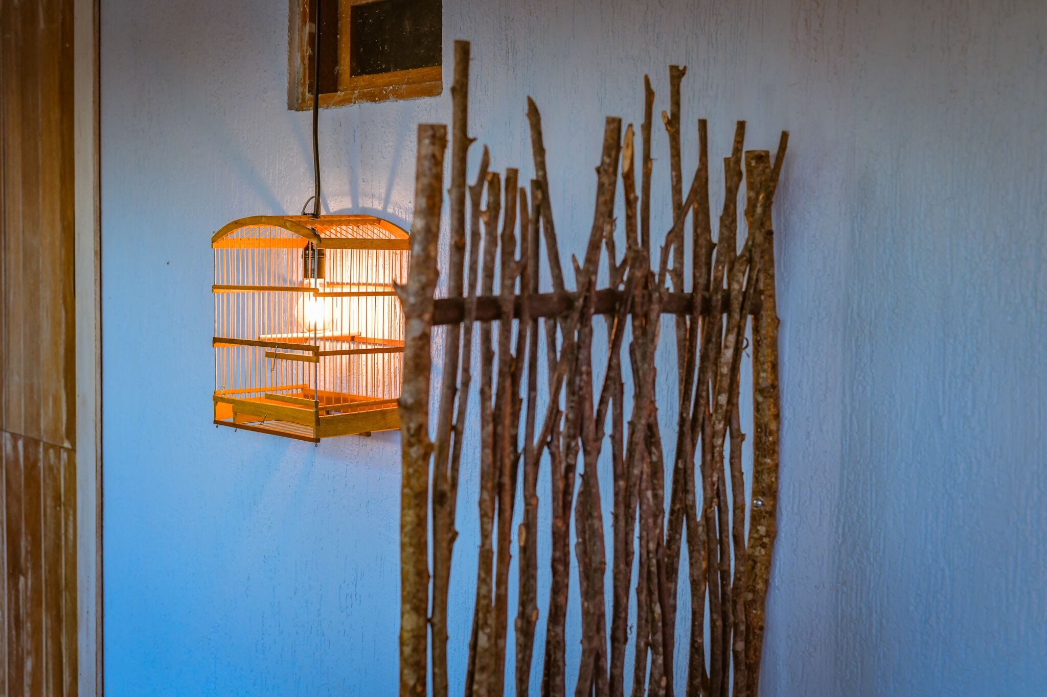 A wall-mounted wooden branch structure with a hanging light fixture.