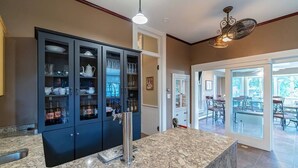 A kitchen with dark cabinets, a marble countertop, and a ceiling fan.