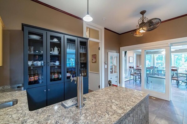 A kitchen with dark cabinets, a marble countertop, and a ceiling fan.