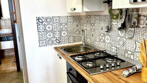 A kitchen with a wooden countertop, a gas stove, a dishwasher, and patterned backsplash tiles. - Charming tourist apartment (Bagheria)