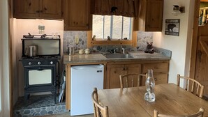 Una cocina rústica con armarios de madera, salpicadero de piedra, una figurita de oso y un reloj en la pared.