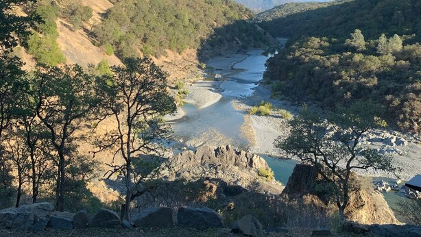 Vista desde un espacio techado con vistas a un valle fluvial y una chimenea en primer plano.