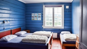 A room with two beds, a window with a view, and a wall with pictures.