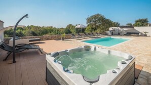 Ein Poolbereich auf dem Dach mit Whirlpool, Liegestühlen und einer Steinterrasse.