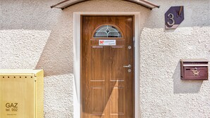 A wooden door with a welcome sign, a mailbox, and a number '3' sign on a textured wall. - 4 bedroom awesome home in Kobylnica (Kobylnica)