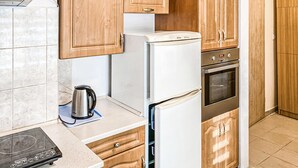 A compact kitchen with a built-in oven, a refrigerator, and a kettle on the countertop. - 4 bedroom awesome home in Kobylnica (Kobylnica)