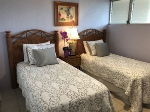 Ein Hotelzimmer mit zwei Einzelbetten, einem Nachttisch mit Lampe und einem gerahmten Bild an der Wand.