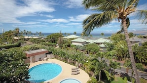 Ein Resort mit Schwimmbad, Palmen und Blick aufs Meer.