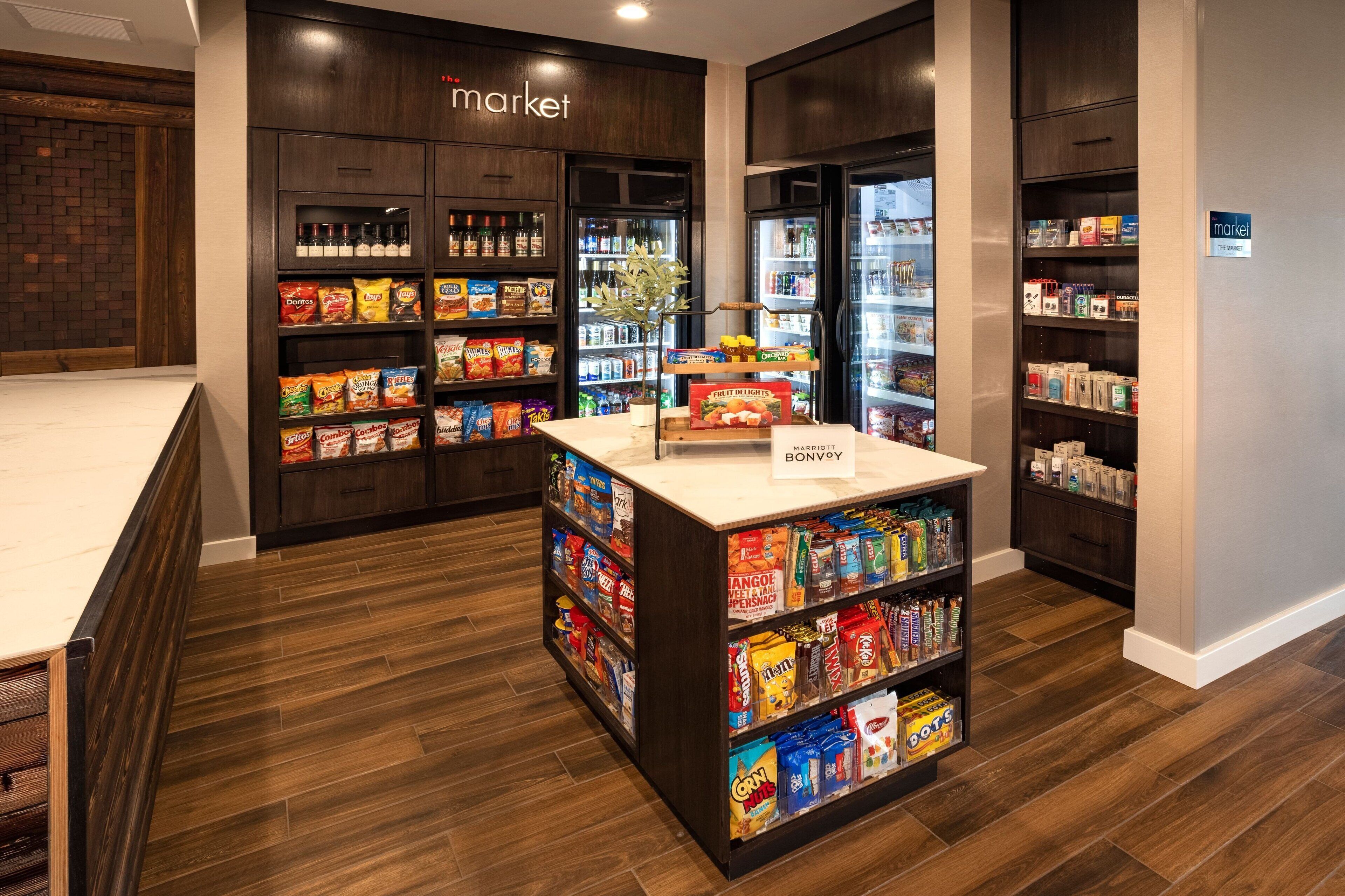 Interior de una tienda de comestibles con suelo de madera, estantes repletos y una zona de exhibición central.