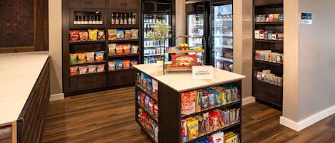 Interior de una tienda de comestibles con suelo de madera, estantes repletos y una zona de exhibición central.