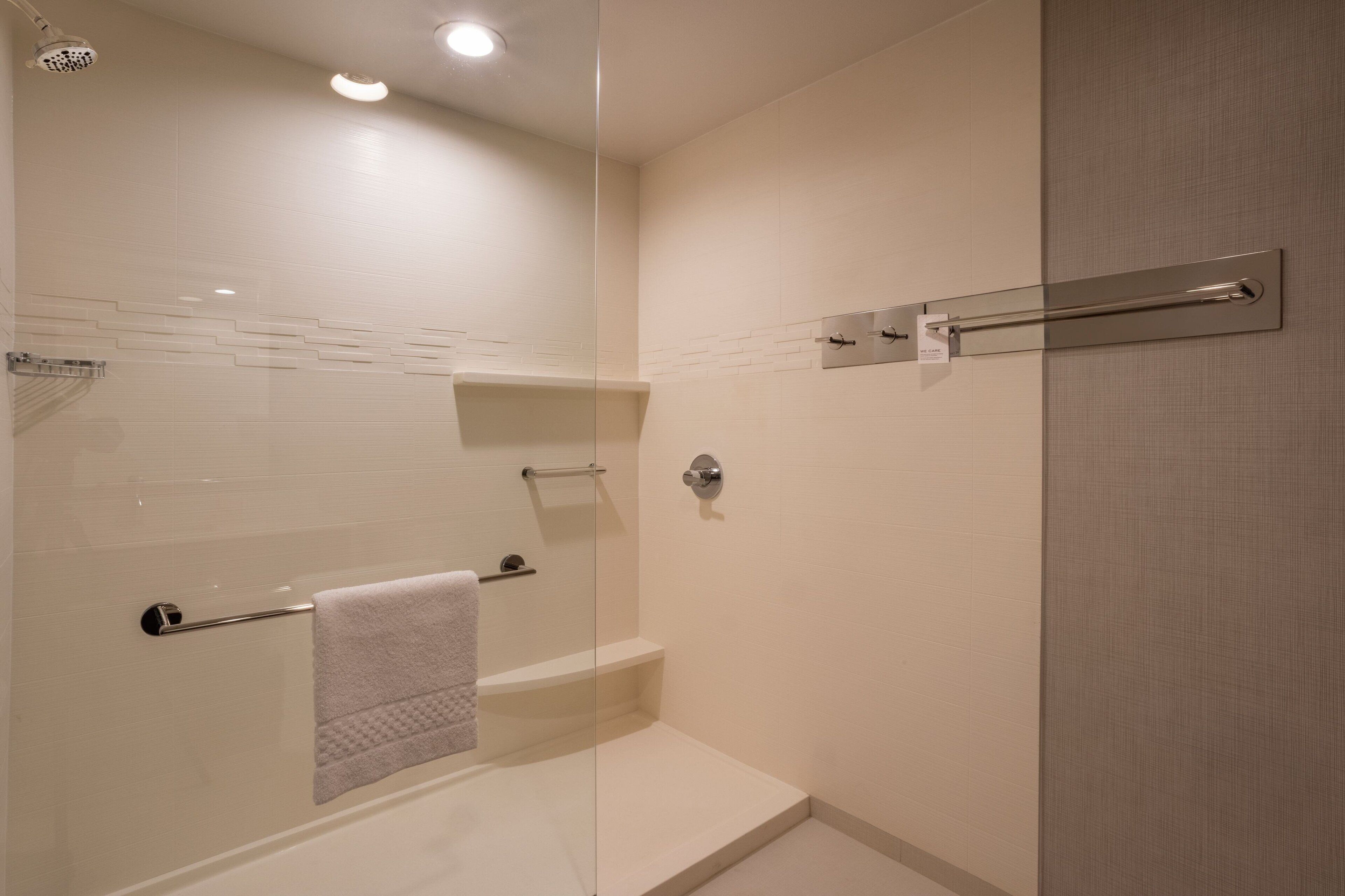 A modern bathroom with a glass shower enclosure, a towel rack, and a built-in shelf.
