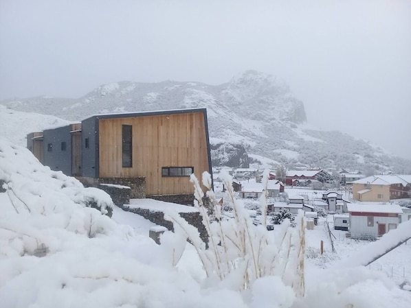 Situated on a slope, this two-story house offers a serene mountain backdrop.