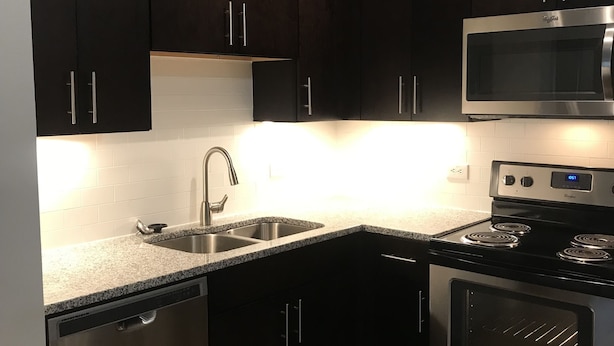 A modern kitchen with dark cabinets, stainless steel appliances, and a granite countertop. - One Bedroom Peachtree Atlanta GA (Dunwoody)