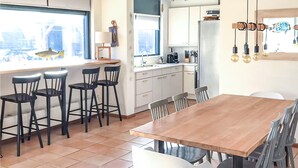 Een moderne keuken met witte kasten, een houten eettafel en barstoelen.