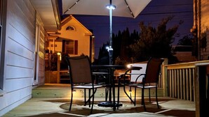 Een terras buiten met een tafel, stoelen, een grote parasol en een lantaarn.