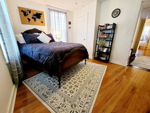 A bedroom with a bed, a world map on the wall, a bookshelf, and a wooden floor. - Apple Hill Bungalow, Family and PET Friendly! (Bristol)