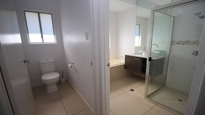A bathroom with a toilet, a sink, and a glass-enclosed shower area.