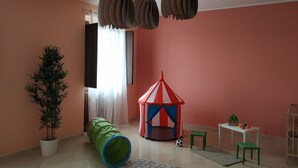 A room with a play tent, a green barrel, a potted plant, and a small table with toys. - Spacious apartment near the beaches and at the foot of Mount Etna (Mascali)