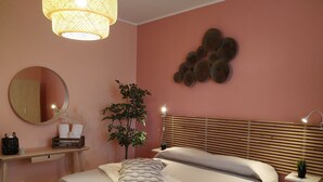 A bedroom with a bed, bedside table, lamp, mirror, and a wall decoration. - Spacious apartment near the beaches and at the foot of Mount Etna (Mascali)