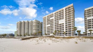 Ein Strandhotel mit mehreren Hochhäusern, einem Sandstrand und Palmen.