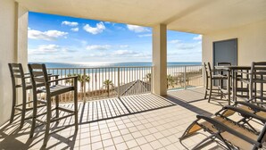 Ein Balkon mit Blick auf Strand und Meer, ausgestattet mit Stühlen und einem Tisch.
