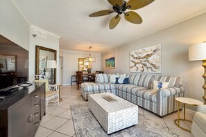 Un salon comprenant un canapé, un pouf et un coin repas avec des chaises et une table.
