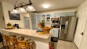 A kitchen with a central island, bar stools, a microwave, a refrigerator, and a sink. - Beautiful home in Kailua-Kona with easy access to all the Island. (KAILUA KONA)