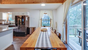 Een ruime keuken met een houten kookeiland, roestvrijstalen apparatuur en een grote eettafel met een gestreept tafelkleed.