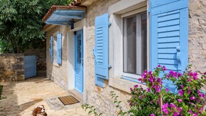 A stone building with blue shutters and a dog in the foreground. - 2 bedroom beach front home in Vabriga (Vabriga)