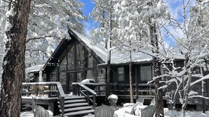 Eine Blockhütte mit Veranda und Sitzbereich im Schnee.
