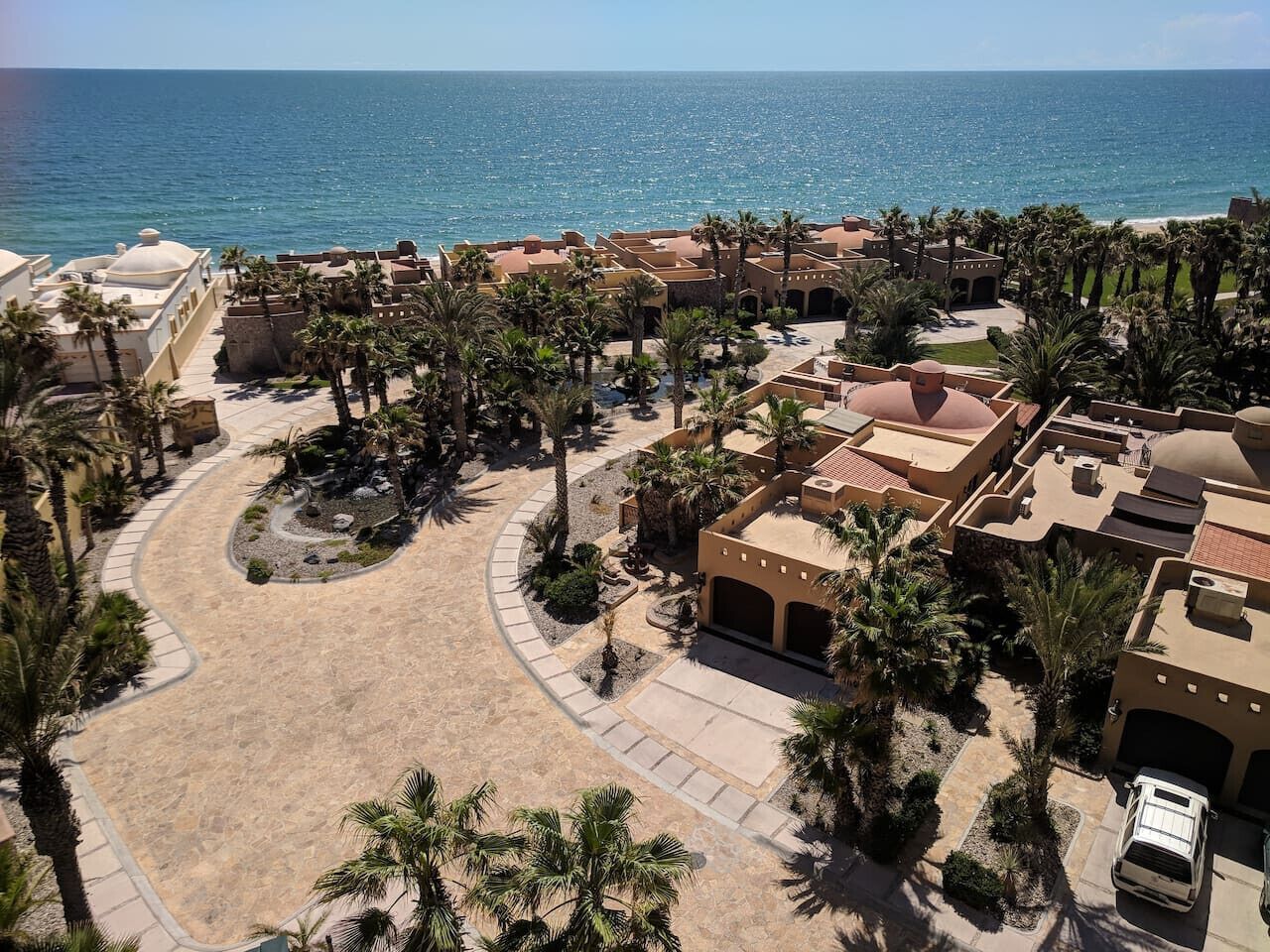 Ein Luftbild eines Resorts mit Strand, Palmen und freiem Blick auf den Ozean.