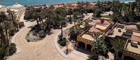 Ein Luftbild eines Resorts mit Strand, Palmen und freiem Blick auf den Ozean.
