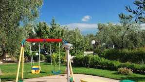 A playground with swings, a slide, and a picnic table. - Bungalow with pool and barbecue (Vieste)