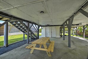 Un espace extérieur abrité, doté d’une table de pique-nique, d’un sol en béton et de poutres métalliques.