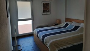 Un dormitorio con una cama, una ventana, un radiador y un cuadro en la pared.