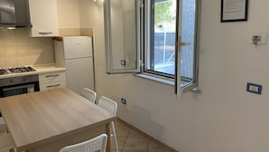 Eine Küche mit Esstisch, Stühlen, Kühlschrank, Herd und einem Fenster mit Ausblick.