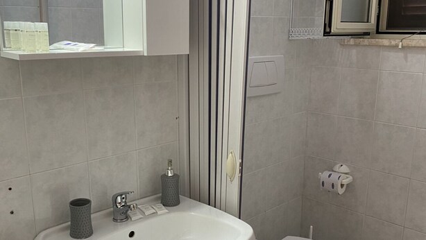 Un baño con un lavamanos blanco, un inodoro y un espejo sobre el lavamanos.