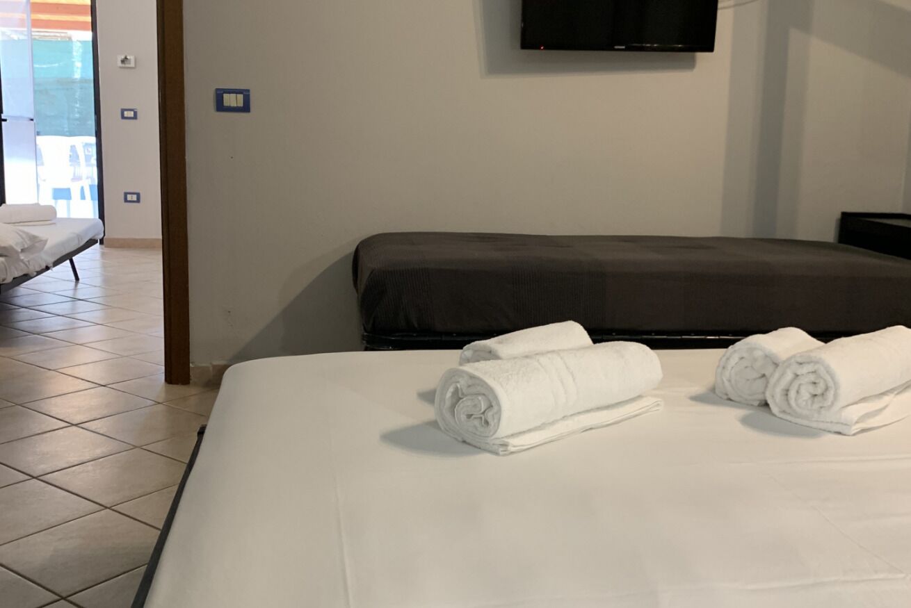 A hotel room with a bed, a TV mounted on the wall, and a bathroom visible through an open door.