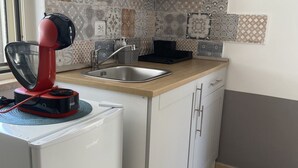 Un angolo cottura funzionale con macchina del caffè, lavandino e piano di lavoro.