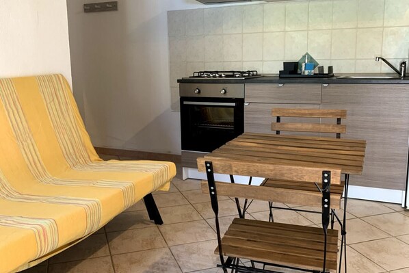 Uma cozinha com fogão a gás, forno e uma mesa de madeira com cadeiras.