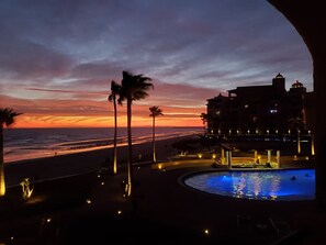 Et resort med pool, strand og udsigt til solnedgang.