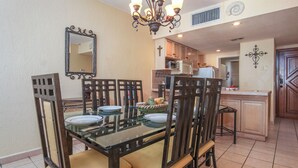 Un coin repas avec une table en verre, des chaises en bois et un lustre.