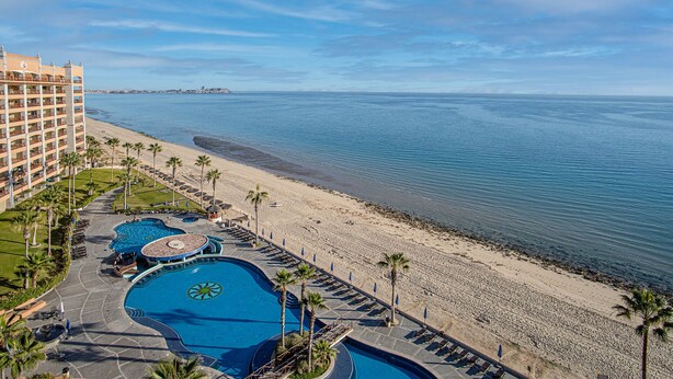 Ein Resort mit mehreren Pools, einem Strand und Meerblick.